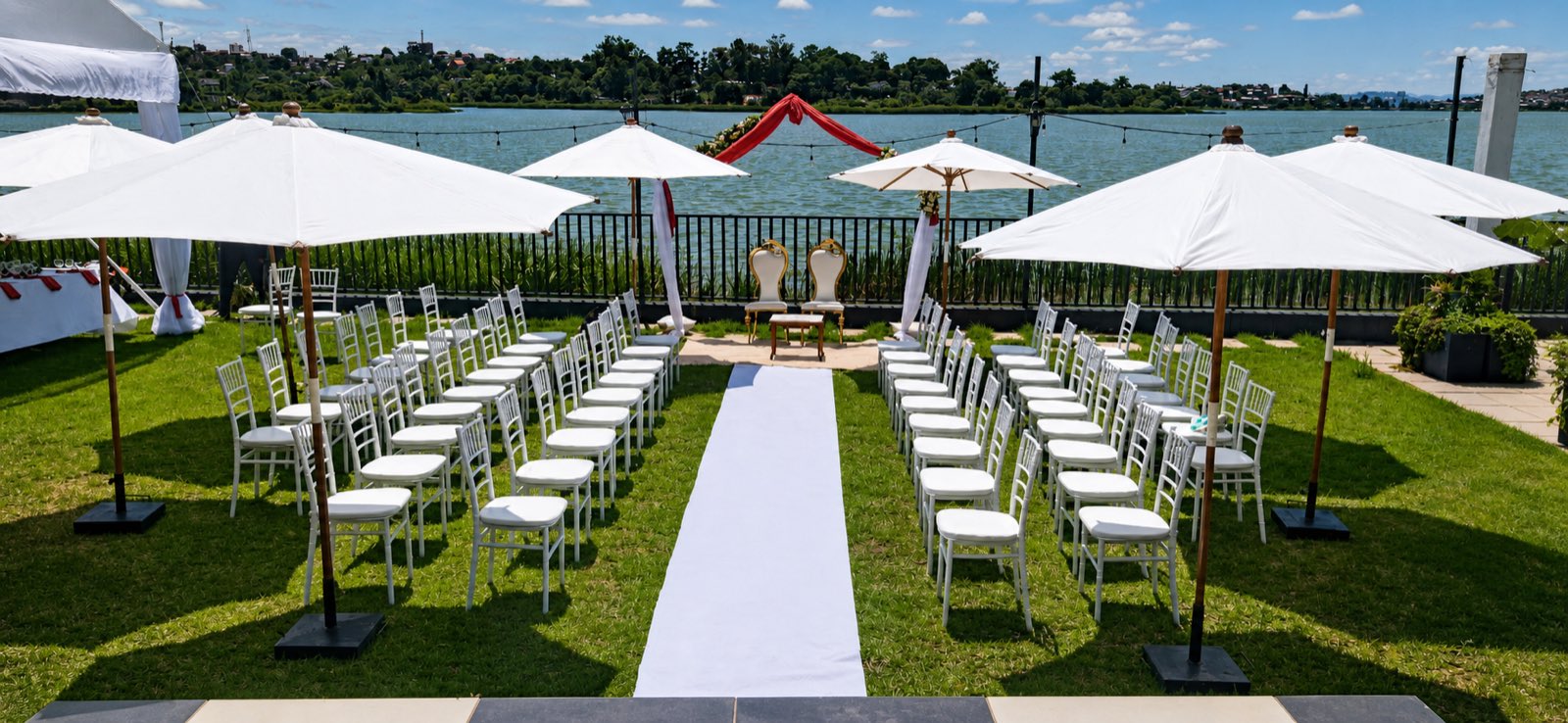Cérémonie dressée face au lac, chaises blanches et parasols